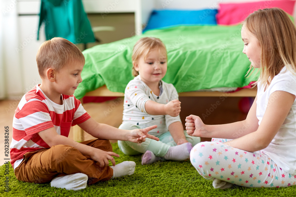 childhood, leisure and family concept - happy little kids playing rock-paper-scissors game at home childhood, leisure and family concept - happy little kids playing rock-paper-scissors game at home
