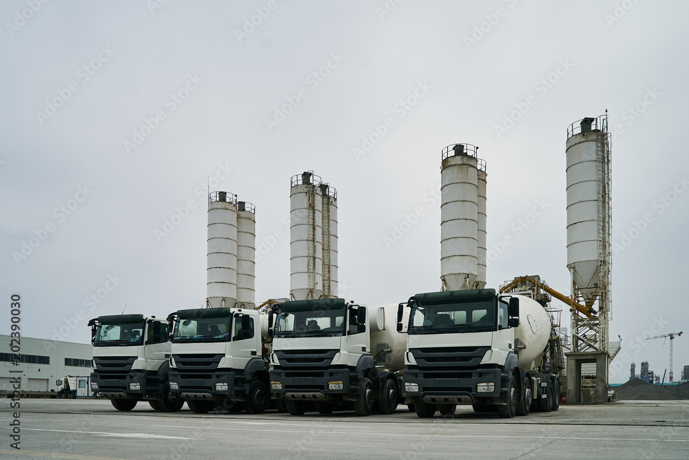 Concrete factory with silos and trucks. Concrete mixing silo, site construction facilities. Industry manufacturing concept Concrete factory with silos and trucks. Concrete mixing silo, site construction facilities. Industry manufacturing concept