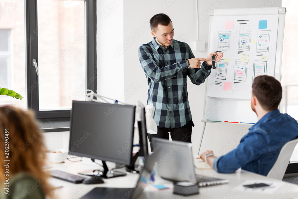 business, technology and people concept - man showing smart watch to creative team at office presentation business, technology and people concept - man showing smart watch to creative team at office presentation