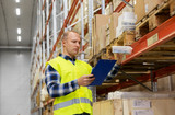 logistic business, shipment and people concept - male worker with clipboard and plastic box in reflective safety vest at warehouse