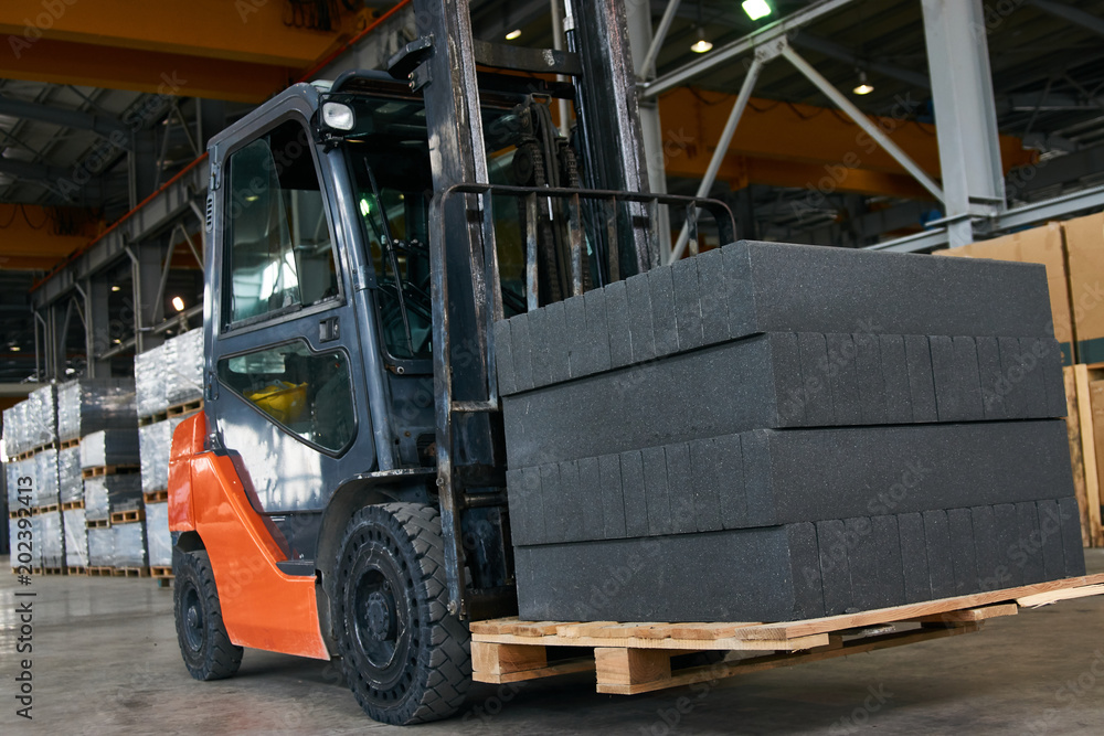 Auto loader with aerated concrete blocks. Forklift truck with slabs working inside factory workshop warehouse