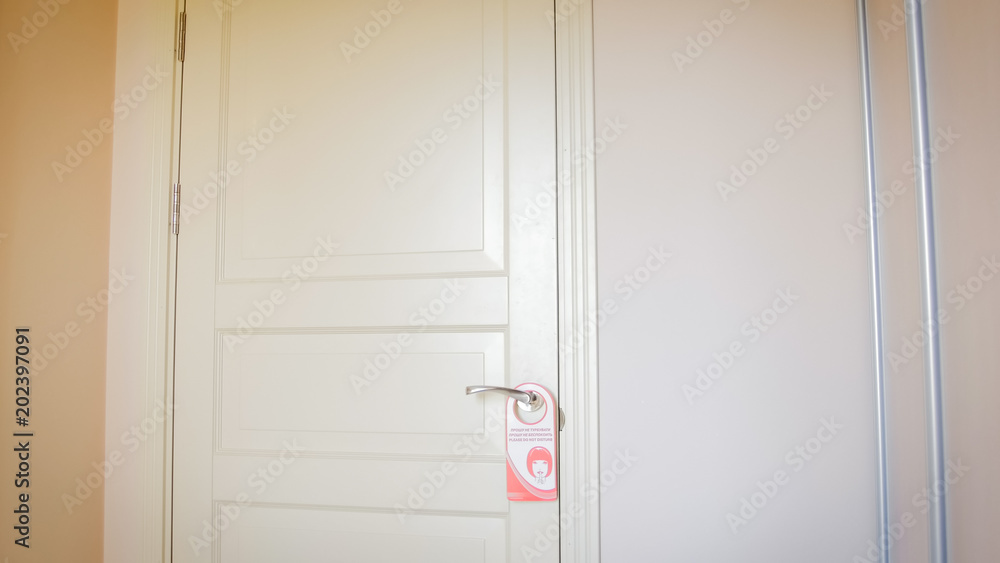 Red do not disturb sign hanging on wooden door at hotel Red do not disturb sign hanging on wooden door at hotel