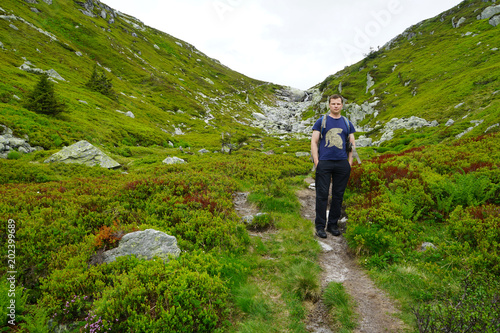 View mountains and a tourist standing on a footpath.