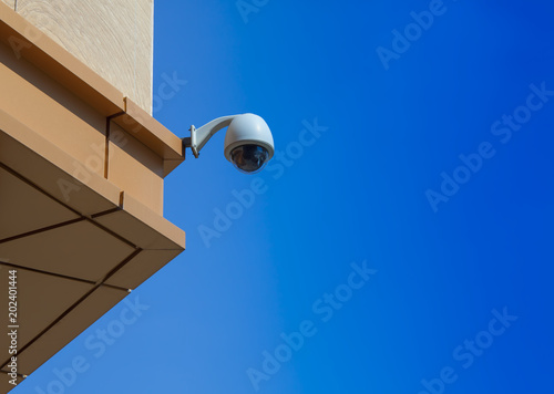 video surveilance camera on a building with clear blue sky background