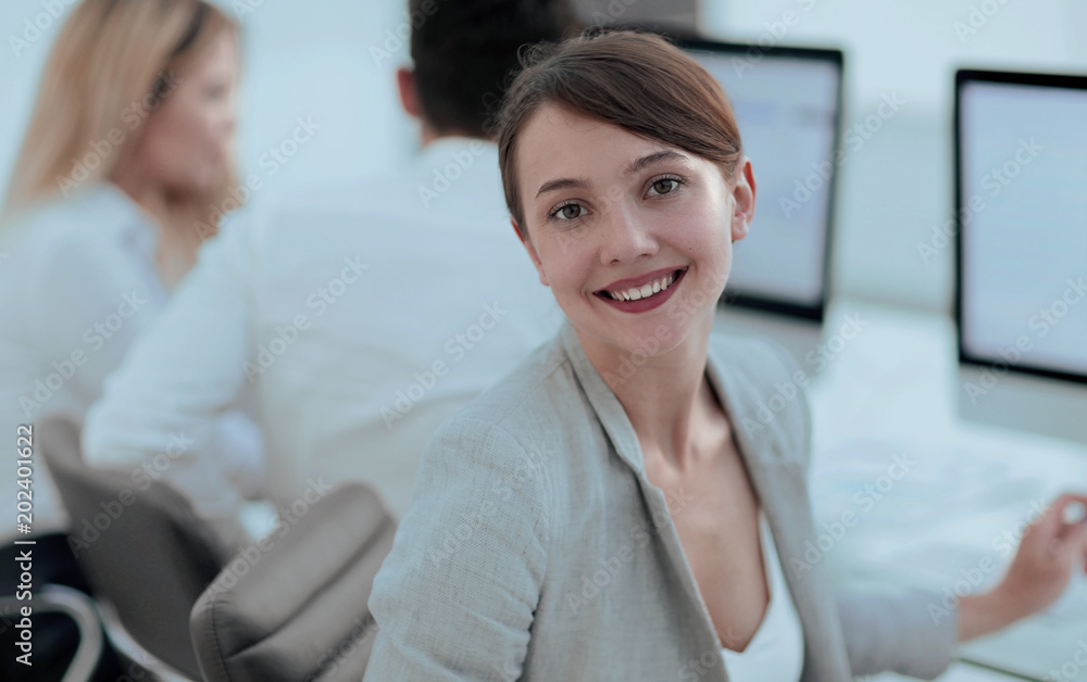 rear view. beautiful business woman sitting near the desktop and looking at the camera. rear view. beautiful business woman sitting near the desktop and looking at the camera.