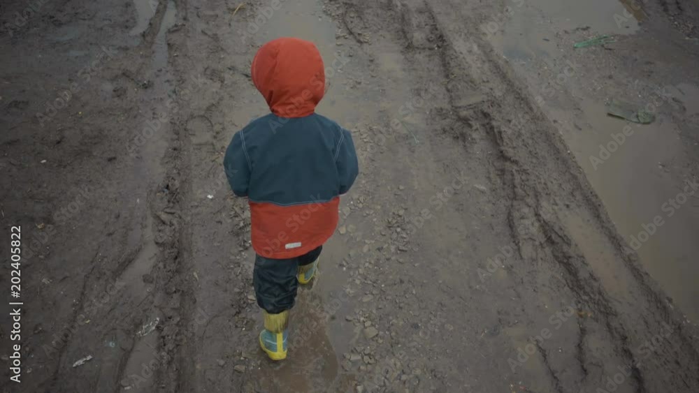 boy walks through the puddles and mud in the spring. boy walks through the puddles and mud in the spring.