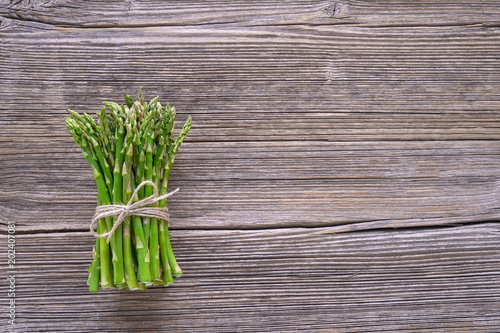 Organic food. Bunch of asparagus on rustic wooden background. Top view  copy space.