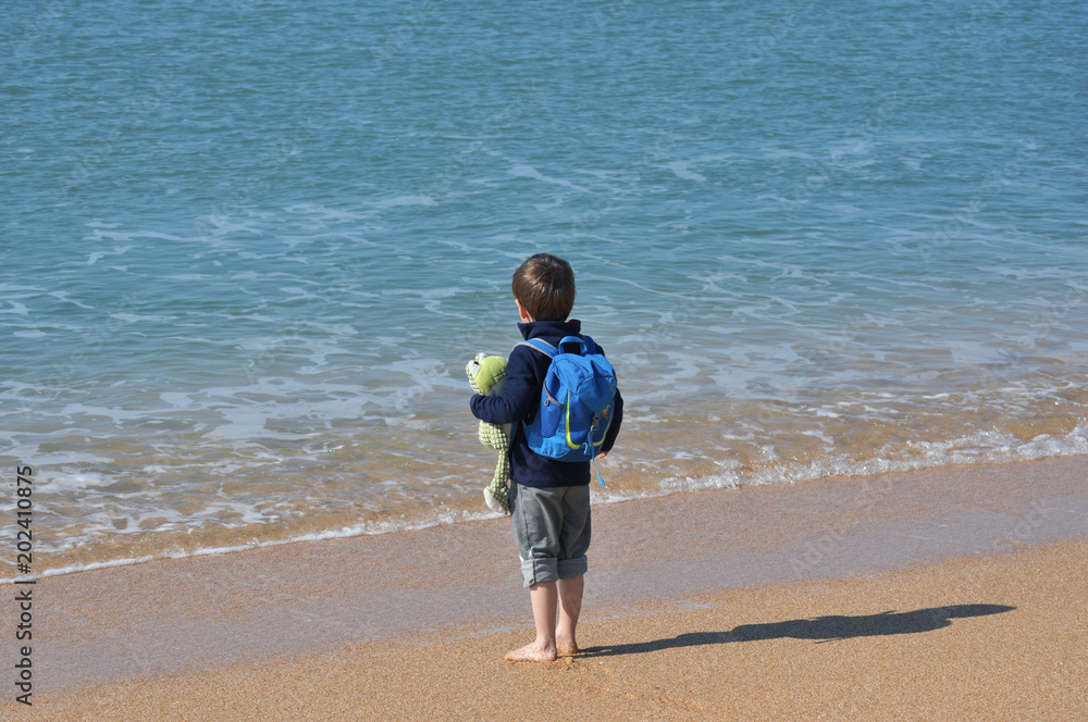 Мальчик босиком с рюкзаком у моря