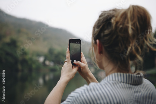 Closeup of a woman hand raising her smartphone up taking a photo of nature travel and tourism concept