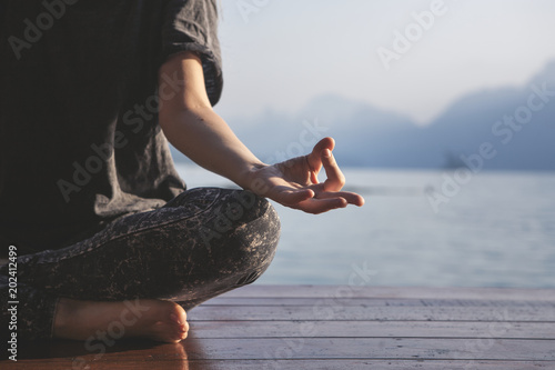 Фотография Woman practicing yoga by a lake
