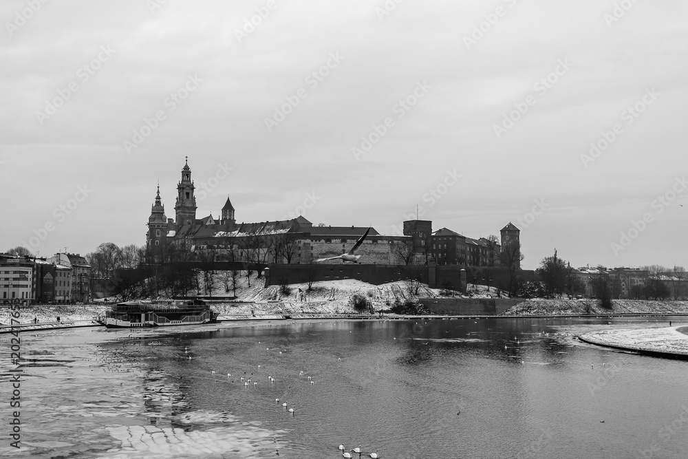 Snowy winter view of Wawel Castle seen from across the Vistula River. Its a cold, cloudy day.Krakow, Poland. Black and white