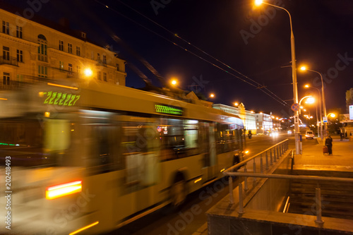 The motion of a blurred trolleybus in the street in the evening.    .