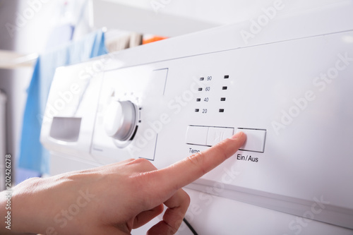 Person Pressing Button Of Washing Machine