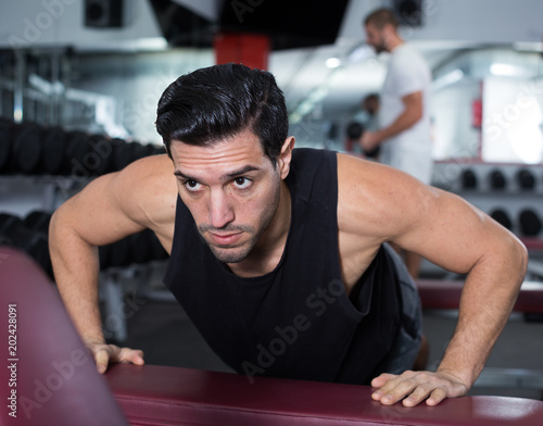 Man doing push-ups on bench in gym