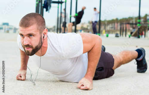 man performs push-ups on sportsground