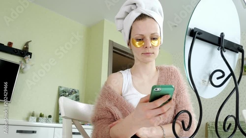 attractive business woman applying cosmetic facial spots at home, talking on the phone photo