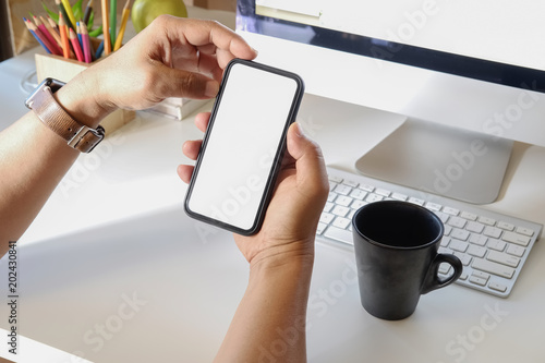 Cropped shot of man holding blank screen mobile phone on desk. Screen smart phone for graphic display montage.
