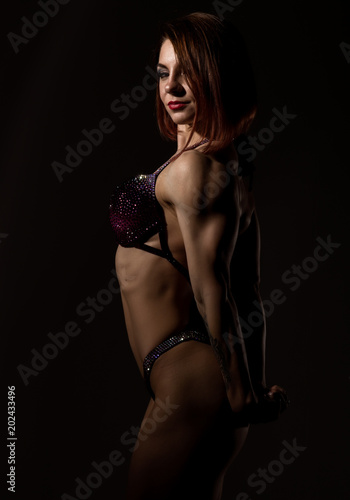 attractive fitness woman  muscles young athlete on dark background