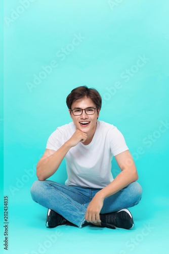 Handsome asian man sitting over blue background. © makistock