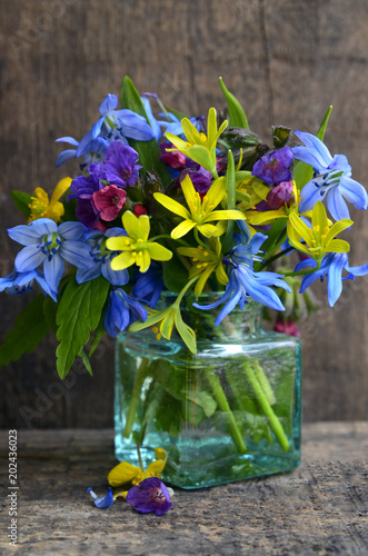 Сolorful spring flowers in a glass vase on old wooden background with space for text.Mother's Day,Birthday or
Springtime greeting card concept.
Selective focus. photo