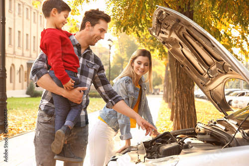 Young family repairing car,...