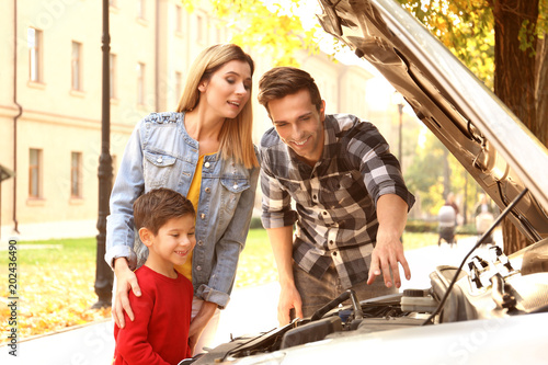 Young family repairing car,...