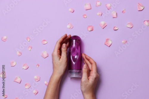 an intimate grease on a pastel background in female hands and rose petals. intimate massage. comfortable sex.  photo