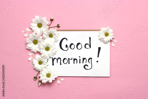 a notebook with the inscription "good morning" and a flower arrangement on a colored background. minimalism, top view. 
