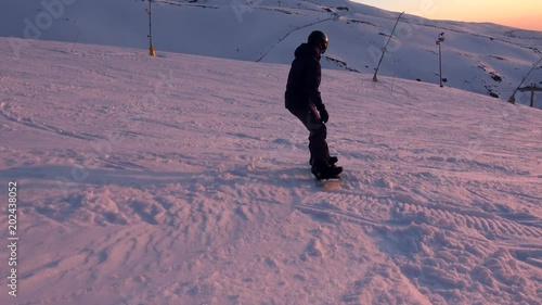 4K. A snowboarder rises from the snow and slides down the mountain, sunset and the mountains are seen in Sierra Nevada, Spain-Adrian.