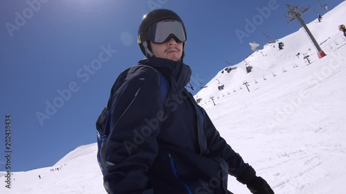 4K. Skiing man is descending a snowy slope on a snowboard. On one side are the chair lifts. Sunny day in Sierra Nevada, Spain-Adrian.
