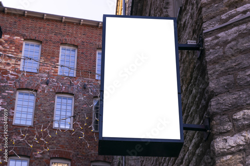 Blank white billboard on city street. In the background street and building. Mock up. Poster on street. Empty space for text. Copy space. Isolated white screen. Mockup for advertising banners