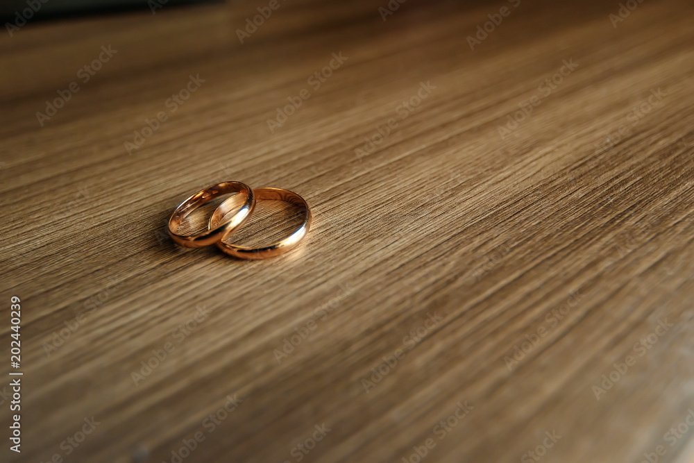 Beautiful picture with wedding rings lie on a wooden surface against the background of a bouquet of flowers Beautiful picture with wedding rings lie on a wooden surface against the background of a bouquet of flowers