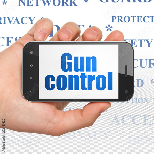 Privacy concept: Hand Holding Smartphone with blue text Gun Control on display, Tag Cloud background, 3D rendering