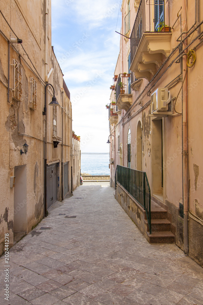 Little street in Sicily. A view to the sea. Italy