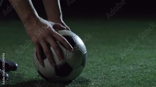 Closeup of feet of professional soccer player putting ball on field with artificial turf, kicking it and running away