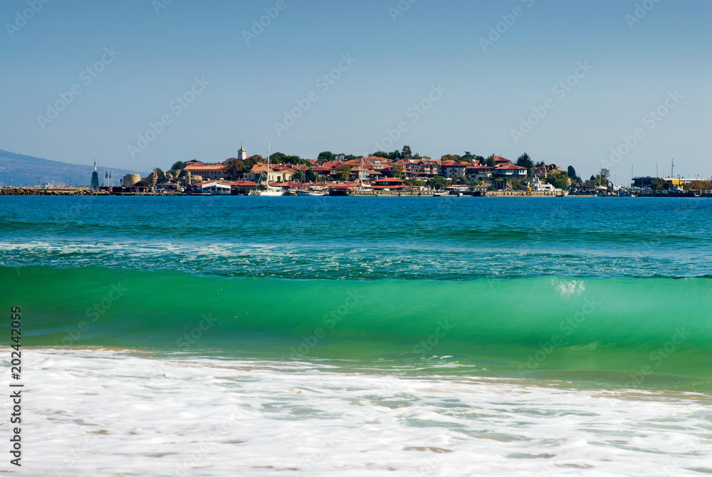 Turquoise sea wave against panorama of ancient Nessebar city, Bulgary