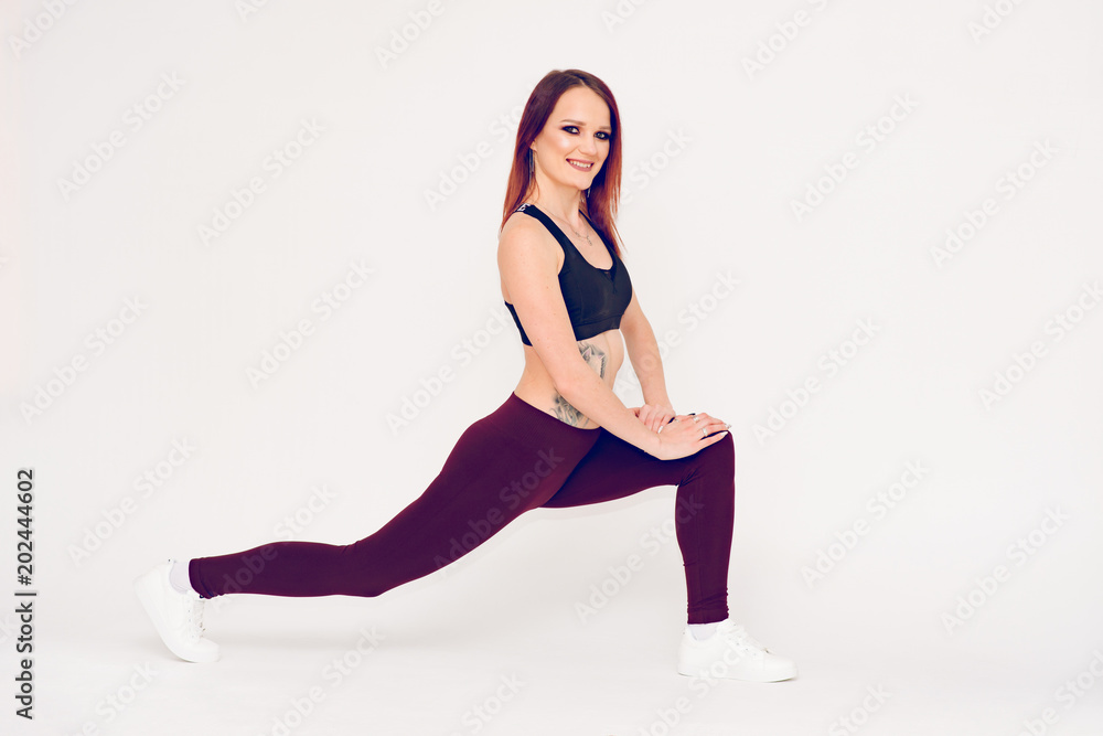 beautiful fitness girl doing stretching legs on white background leaning hands on knees