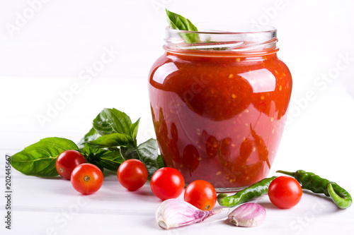 Homemade preserved ketchup in glass jars. On a white background