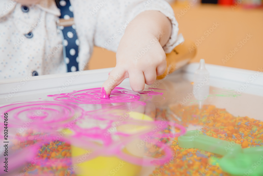 Close-up of child hand draws finger on table with paint, development of kid motor skills Close-up of child hand draws finger on table with paint, development of kid motor skills