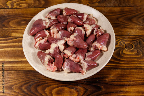 Raw chicken hearts on wooden table