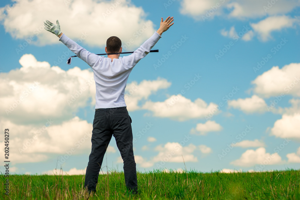 a successful golfer after a successful game enjoys the victory, the view from the back, the hands are raised upwards a successful golfer after a successful game enjoys the victory, the view from the back, the hands are raised upwards