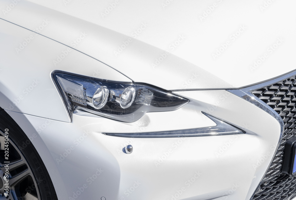 Headlight of a modern white sport car. The front lights of the car. Modern Car exterior details. Car detailing