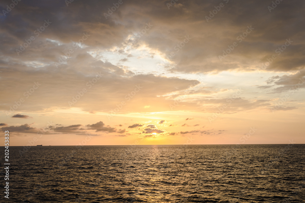 drop of sunset from bright sky above the ocean in evening time