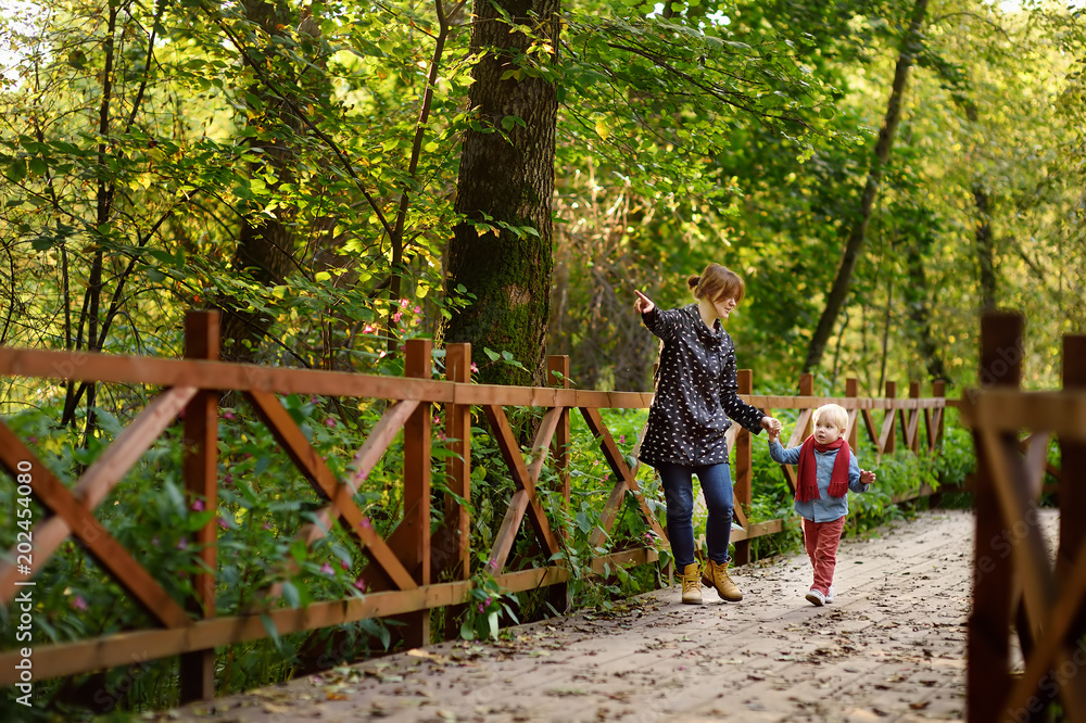 Little boy with his young mother talking during stroll in the forest Little boy with his young mother talking during stroll in the forest