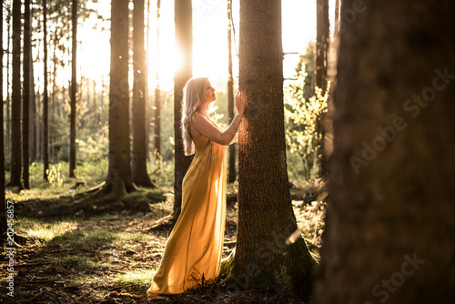 Junge Frau betet im Wald zum Sonnenuntergang photo