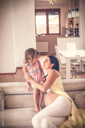 Beautiful pregnant mother and her daughter spending time together.