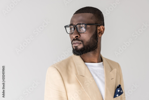 portrait of handsome stylish young african american man in eyeglasses looking away isolated on grey