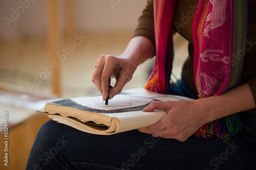 Female hands draws with charcoal portrait in sketchbook