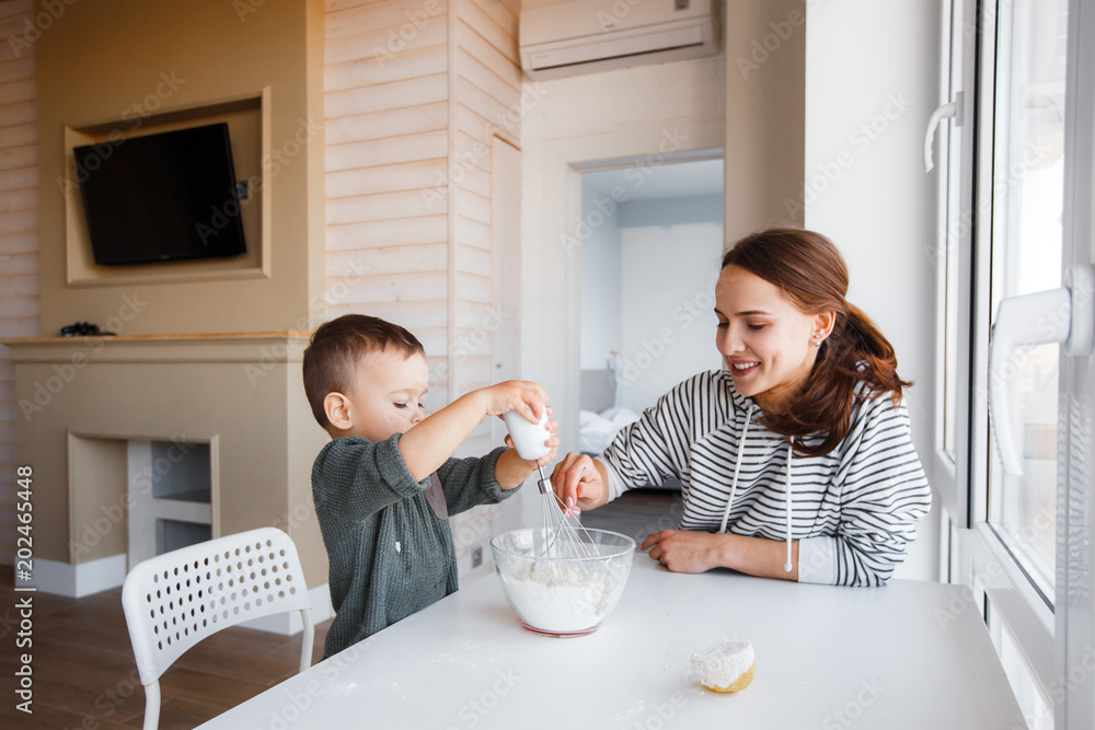 Φωτογραφία Mom with her child cooking holiday pie in the kitchen to Mothers day, casual lif