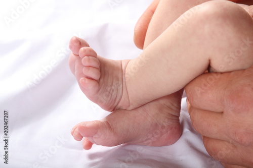 the feet of the newborn and the hands of the father